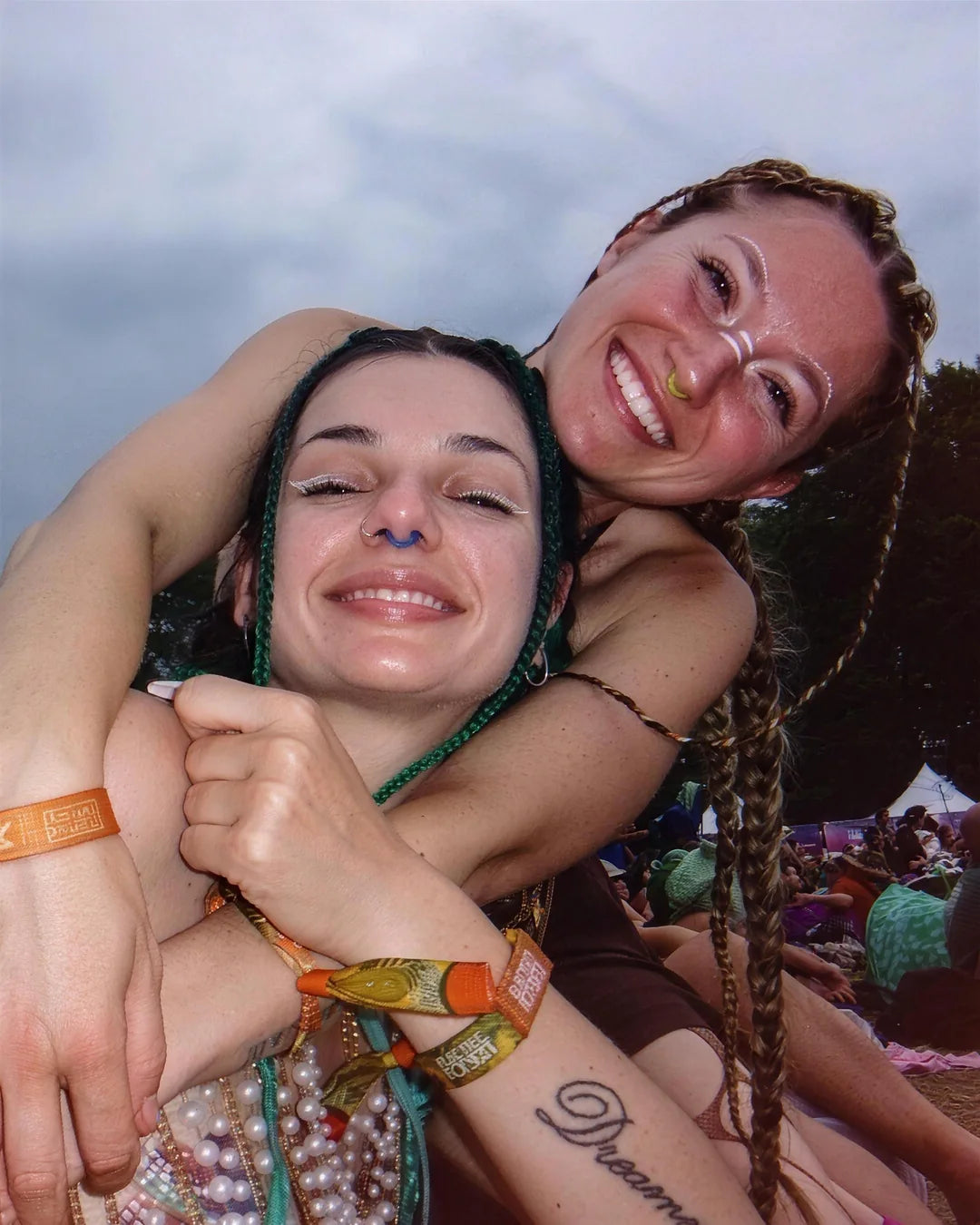 Two friends hugging at a festival, wristbands and kandi on
